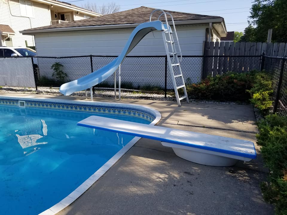 Inground pool with slide and diving board before demolition